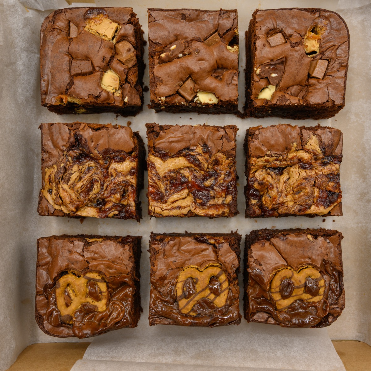 A tray of freshly baked brownies with swirls of caramel and pretzel