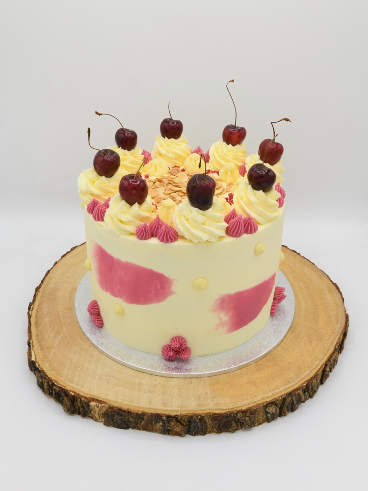 A handcrafted celebration cake decorated with fresh cherries and buttercream